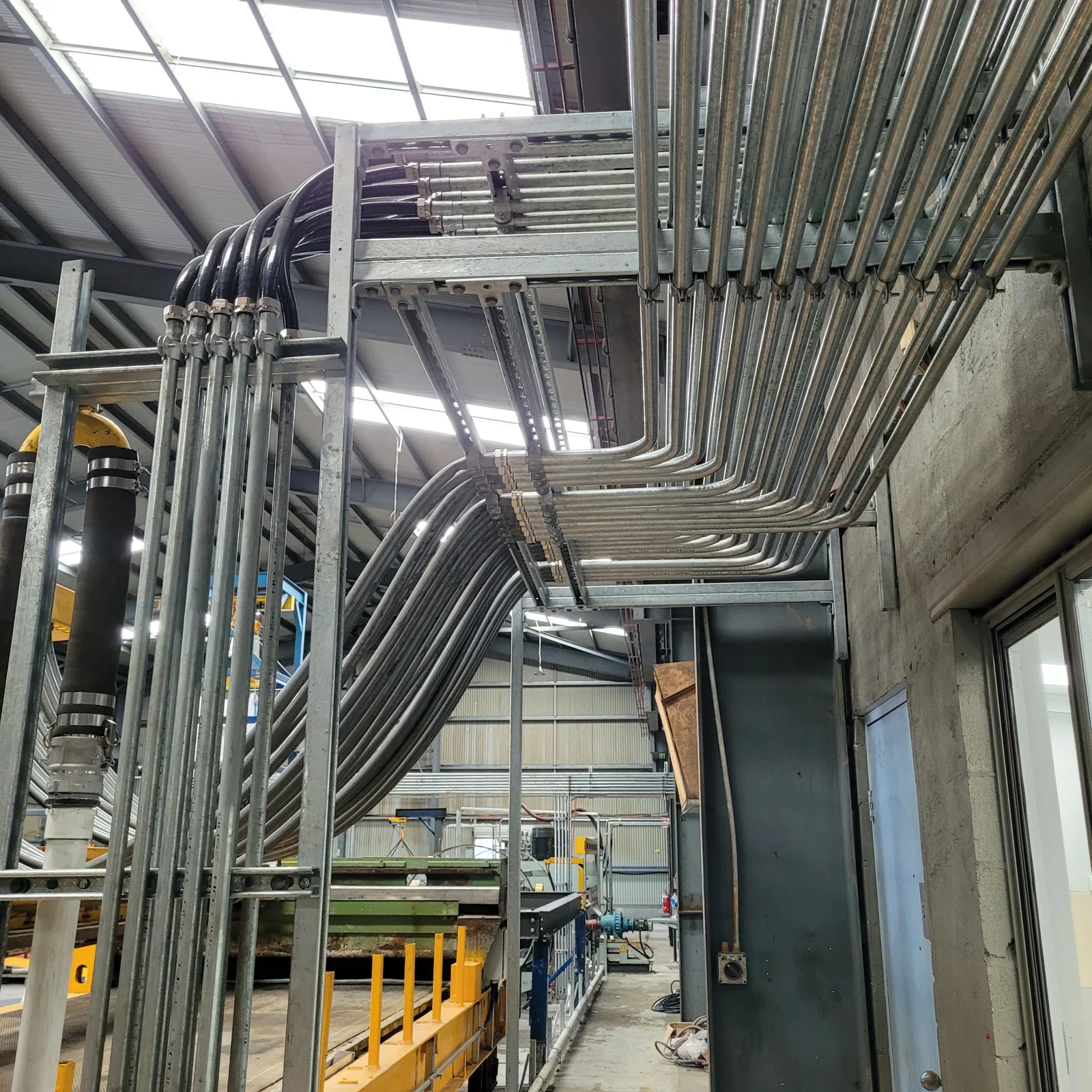 Galvanised conduit runs on steel framing in an industrial facility