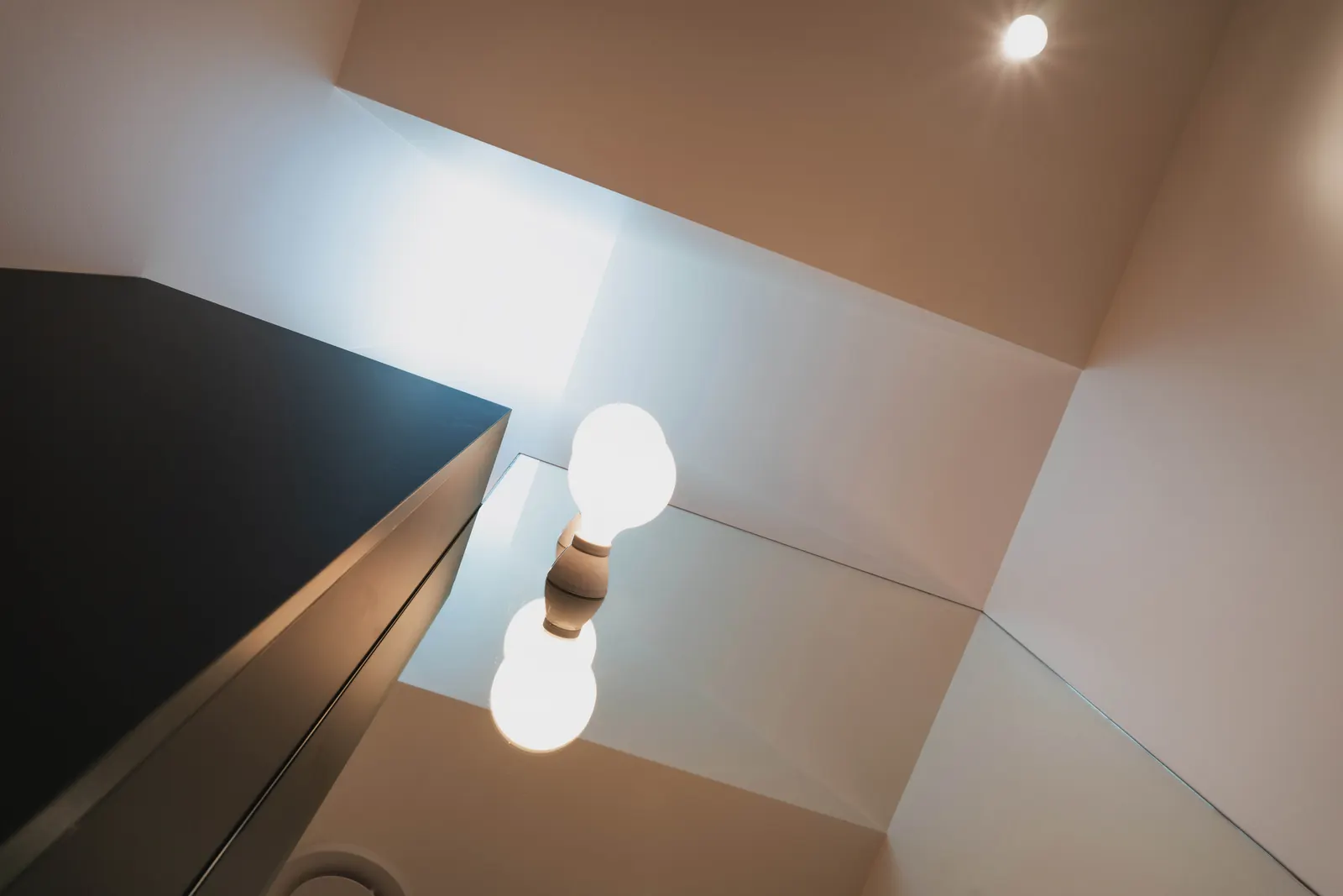 Two globe lights in a tall white ceiling void, seen from below