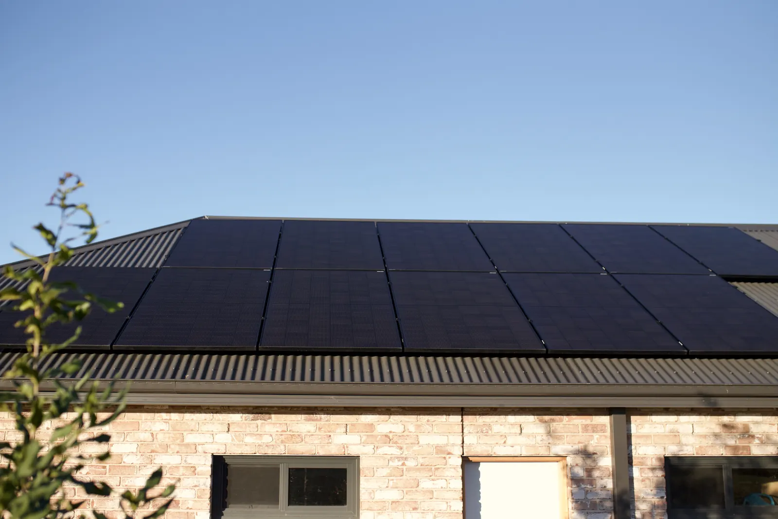 Black solar panels across the roof of a brick house