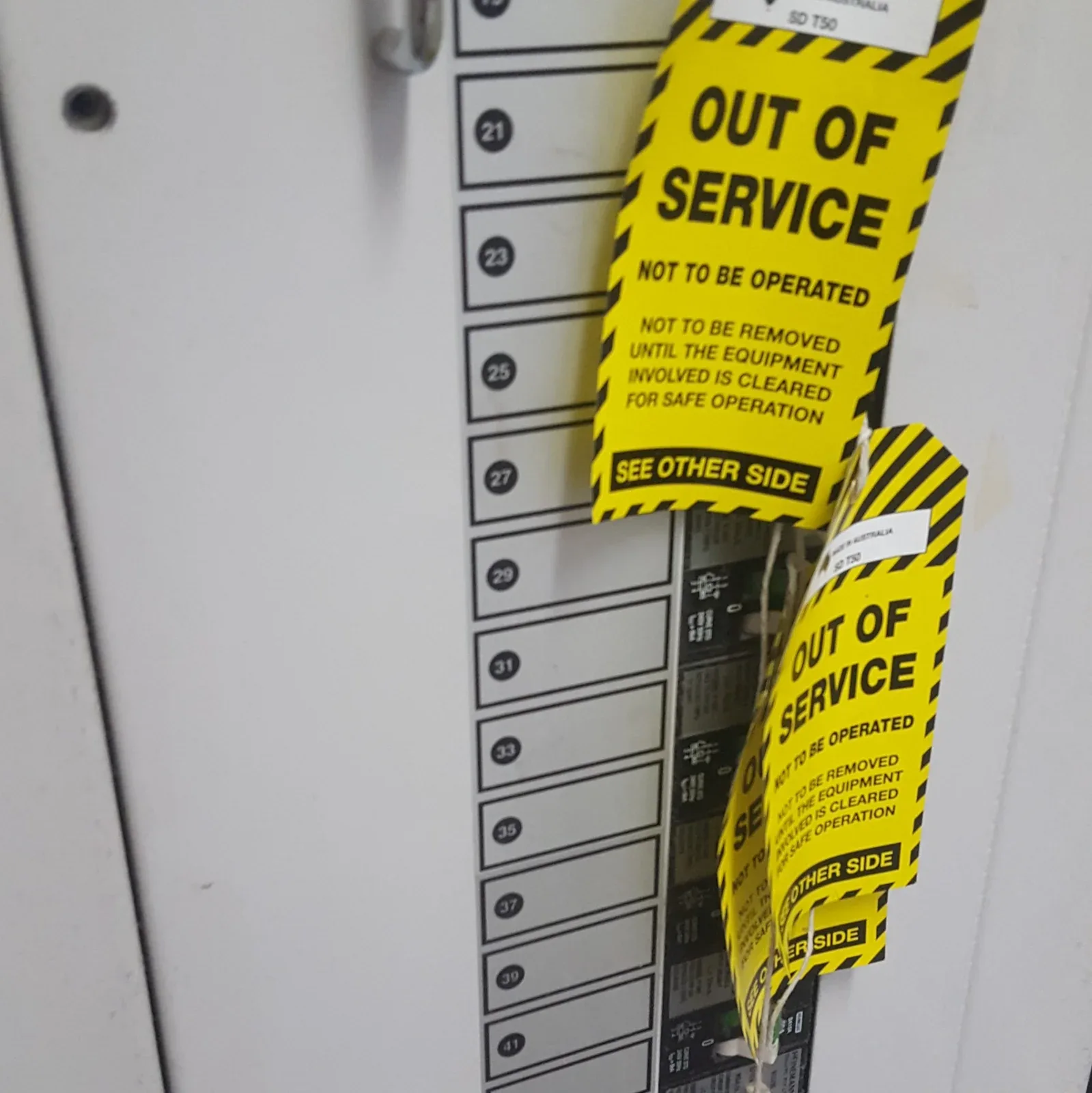 Two OUT OF SERVICE lockout tags hanging from an electrical switchboard