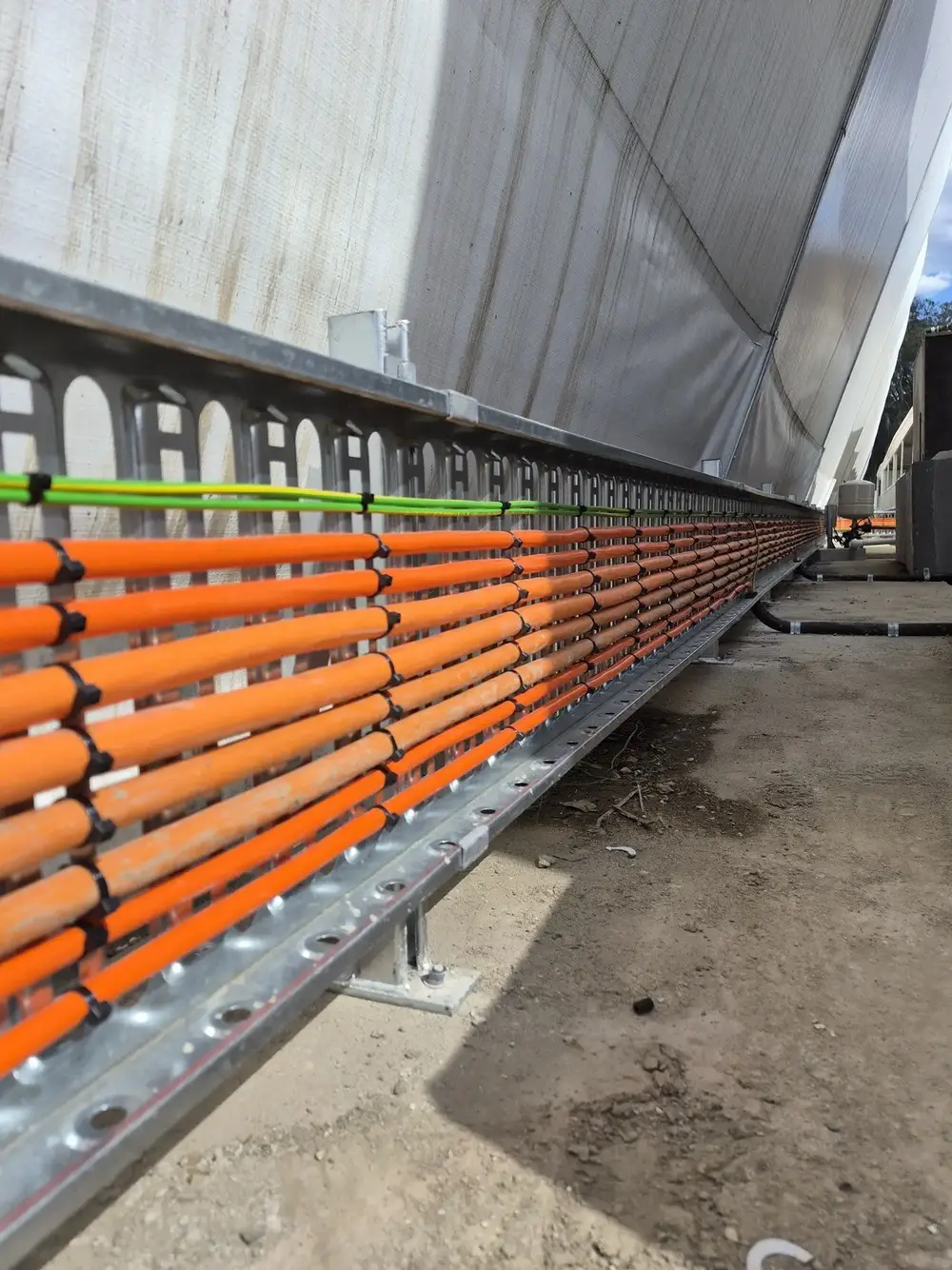 Orange cables cable-tied to a galvanised steel cable tray