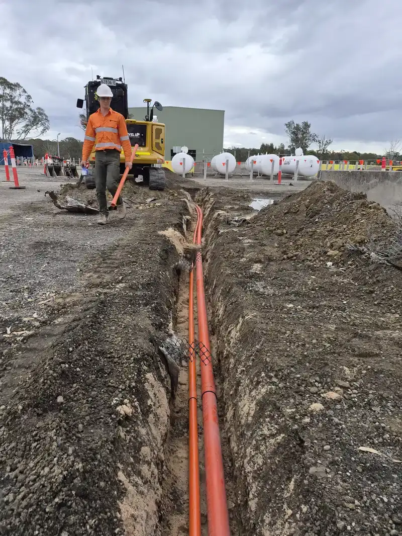 Orange conduit being laid in the underground trench