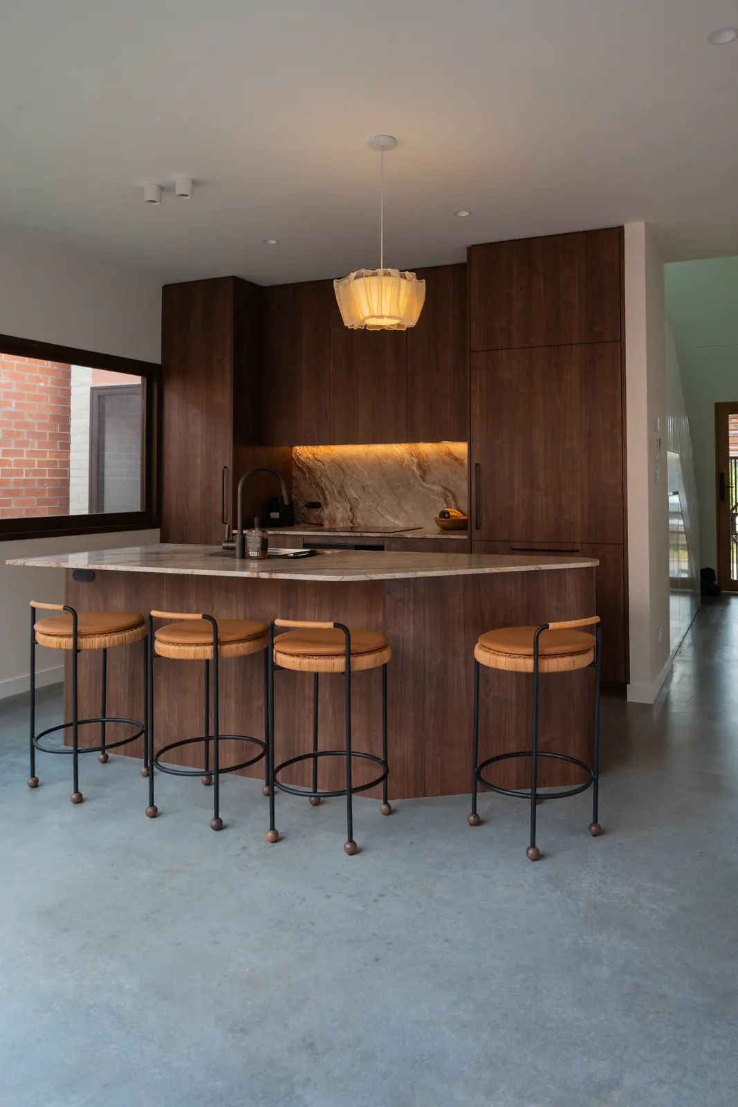 Timber kitchen island with four bar stools and a pendant light above