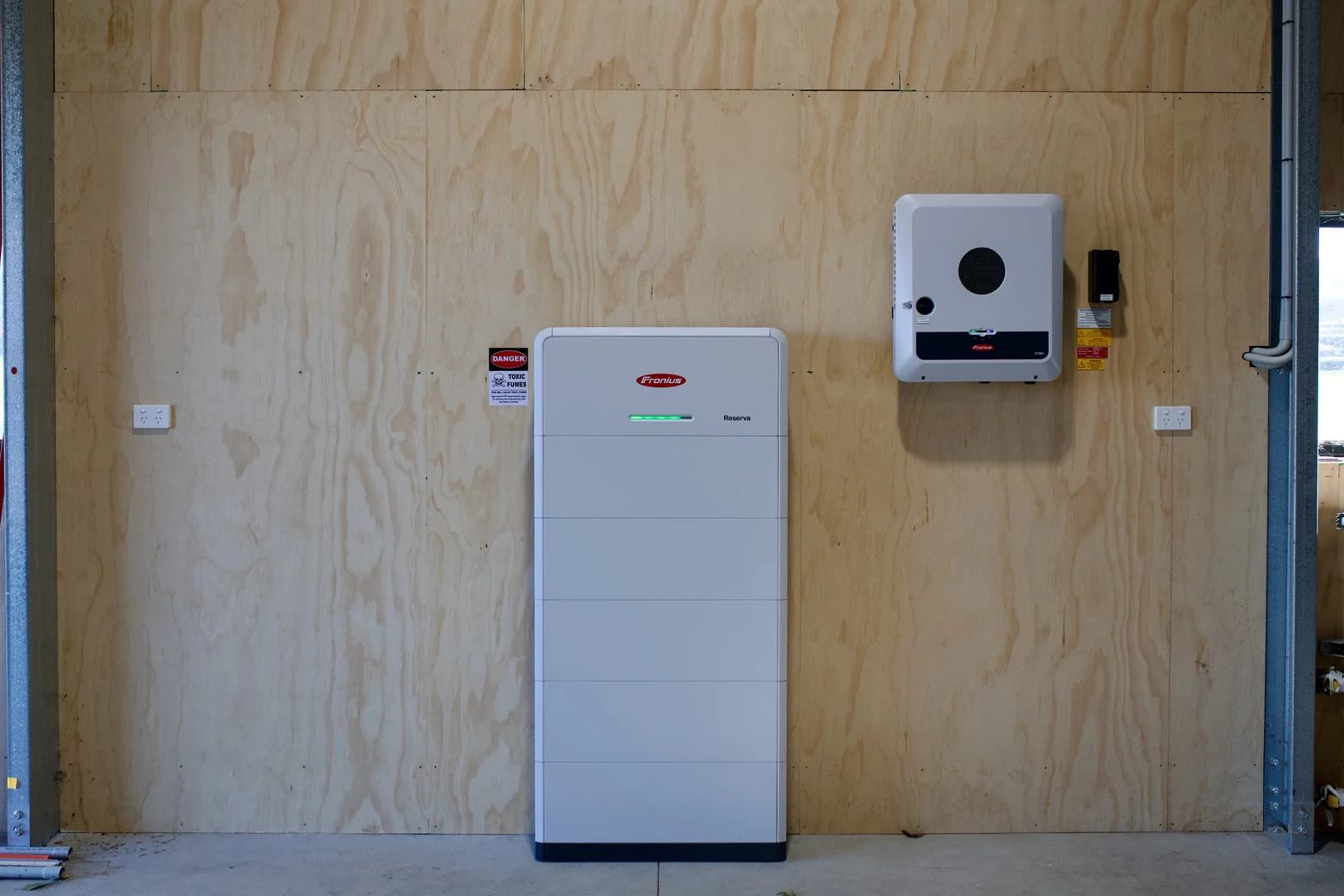 Inverter and battery stack on the plywood wall, with space left for additional batteries and inverter if required