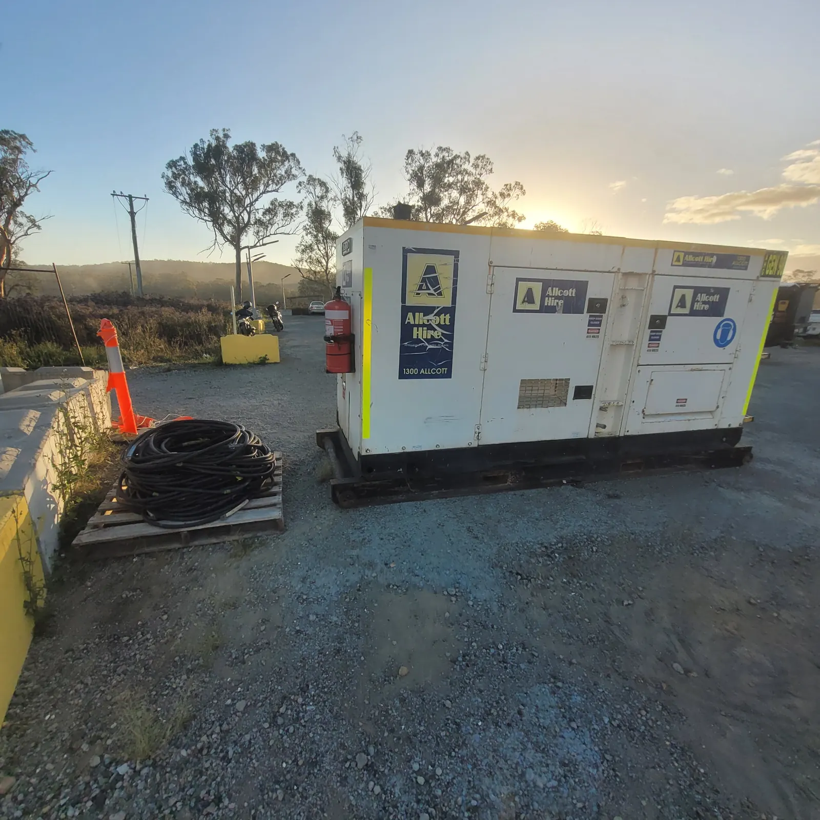 Temporary generator on site, with its connection cables coiled on a pallet
