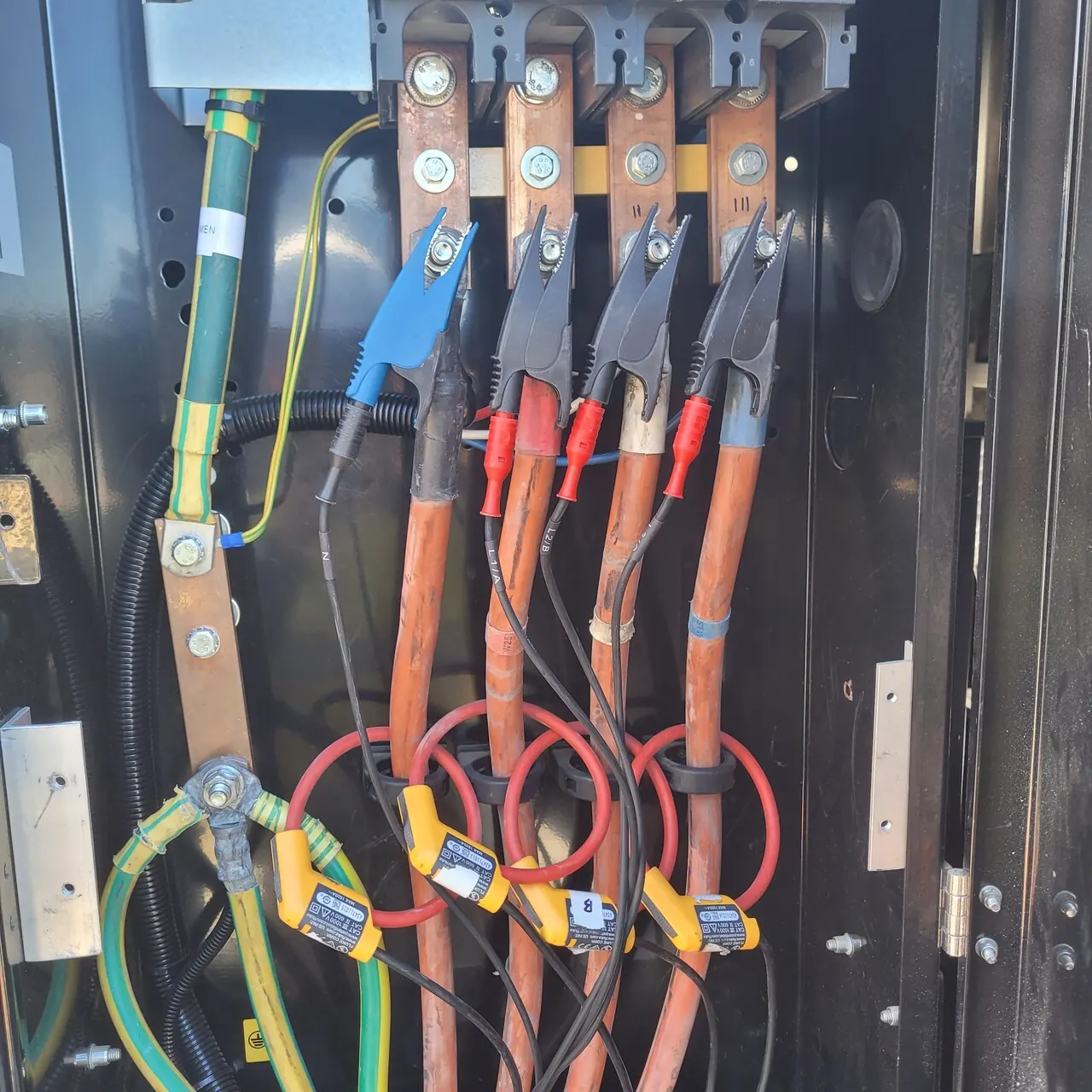 Voltage leads clipped to the busbars and flexible current probes around each cable, connecting the power logger