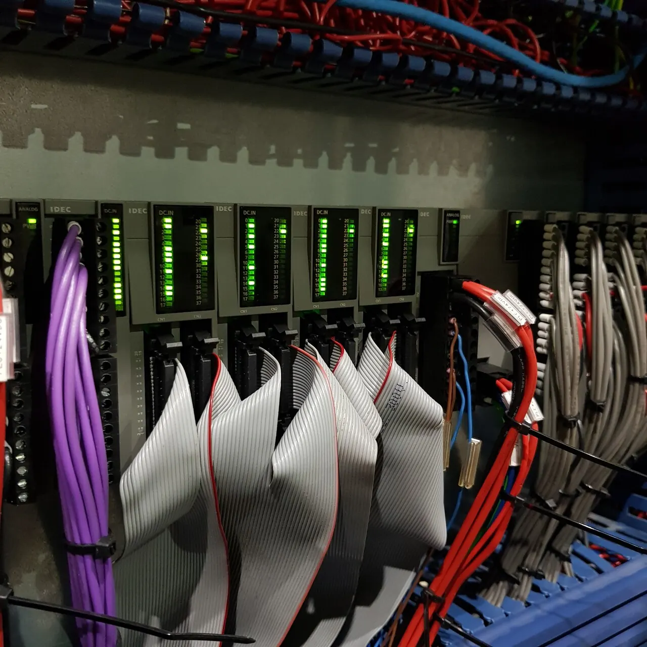 IDEC PLC modules in the control panel, with input status lights on and ribbon cables connected