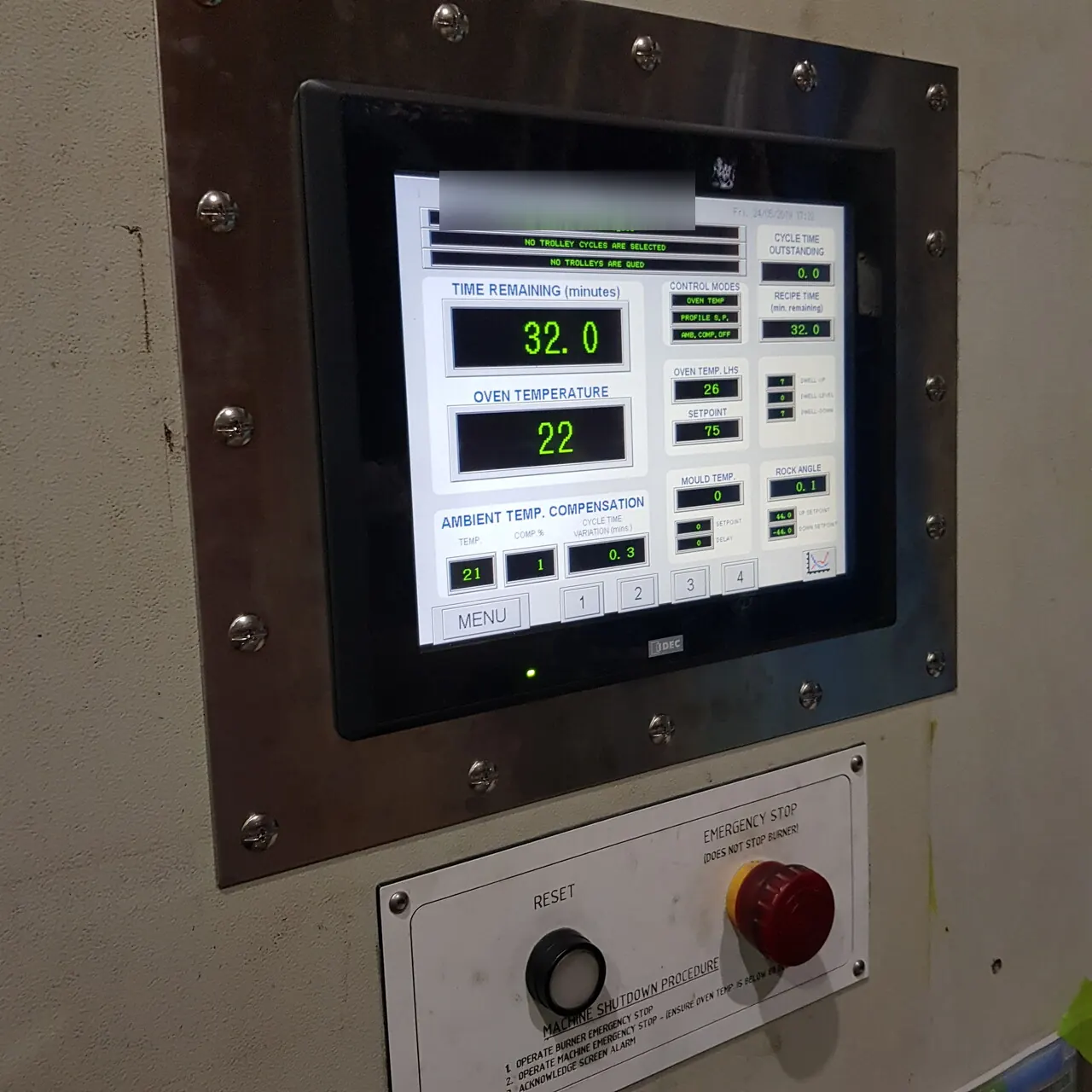 The HMI touchscreen showing time remaining and oven temperature, above the reset and emergency stop buttons