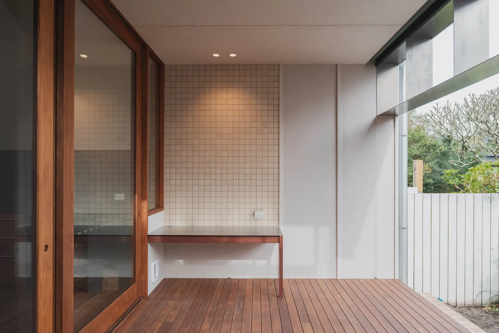 A built-in desk against the tiled wall, with downlights above