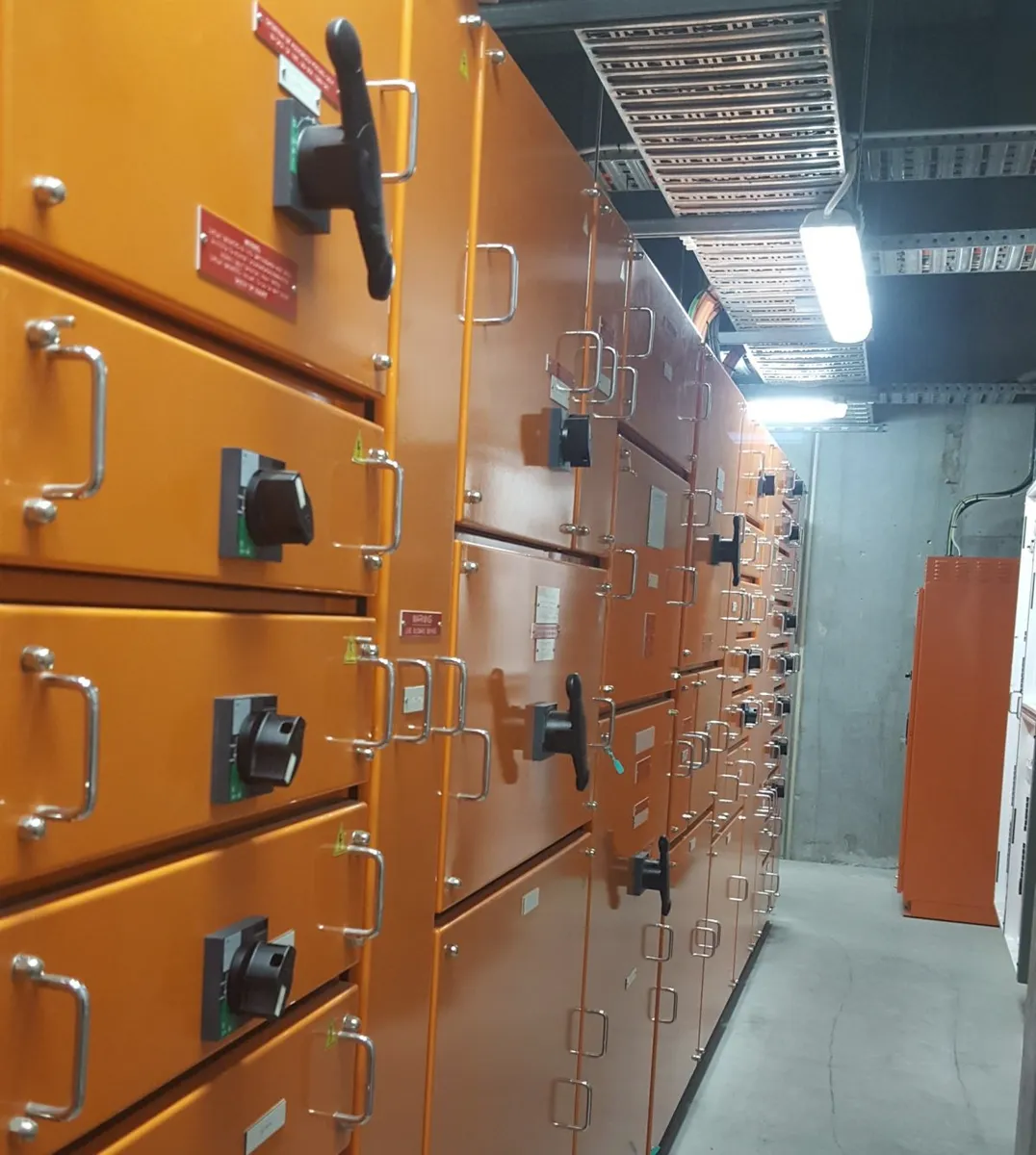 A row of orange switchboard cubicles in a switchroom